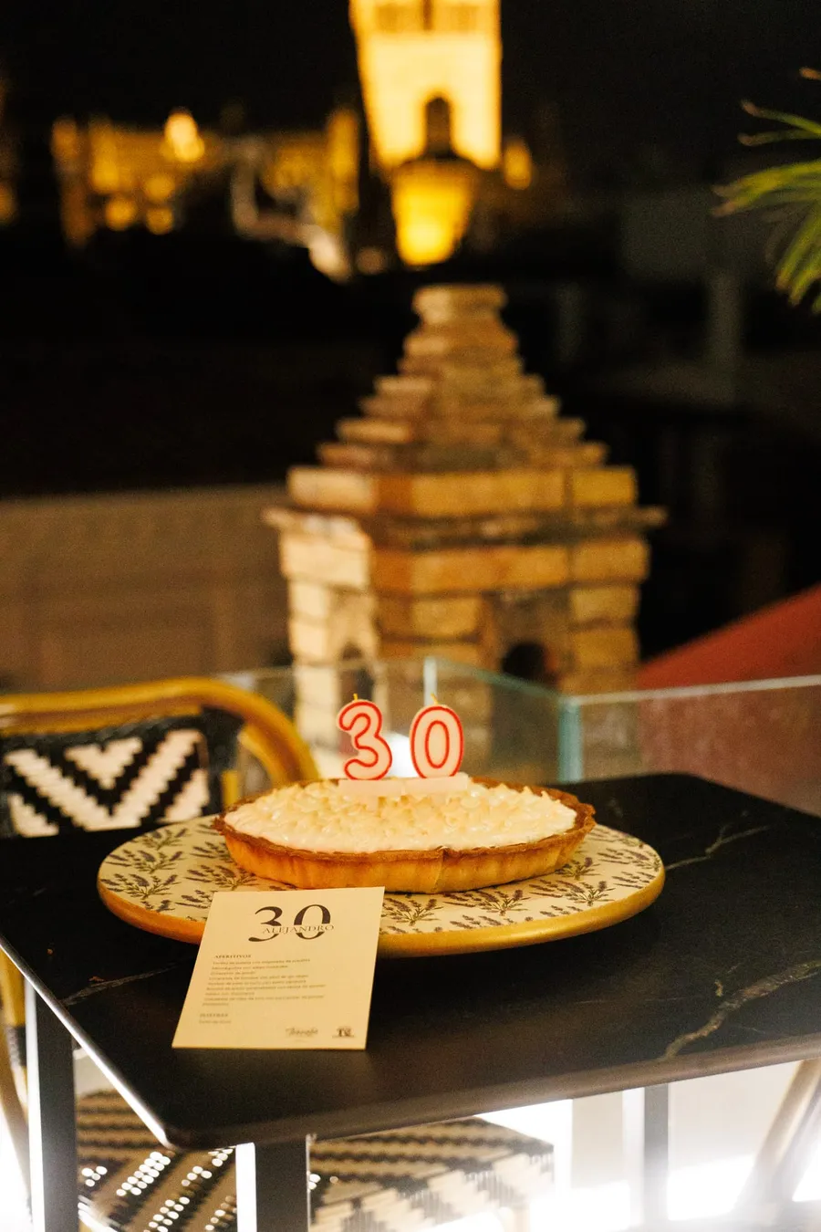 Tarta de cumpleaños con velas de los números 30, con la Giralda al fondo.