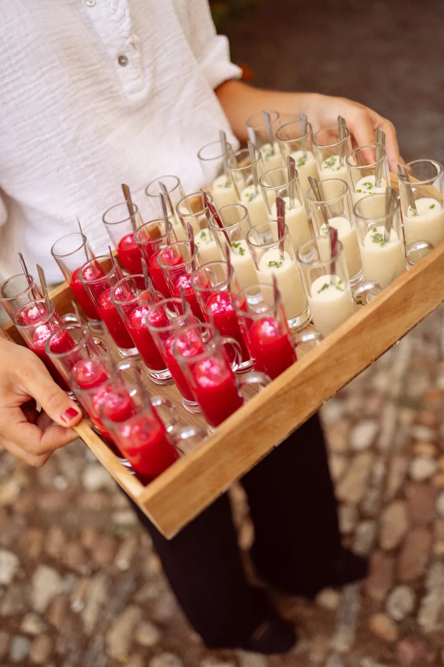 Bandeja de chupitos de gazpacho y salmorejo sujeta con la mano durante un cóctel.